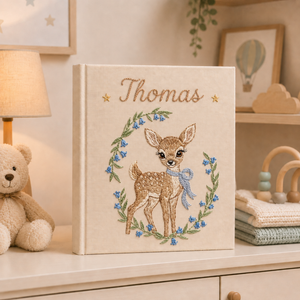 Personalized hand embroidered photo album featuring a woodland fawn surrounded by blue wildflowers and custom name embroidery