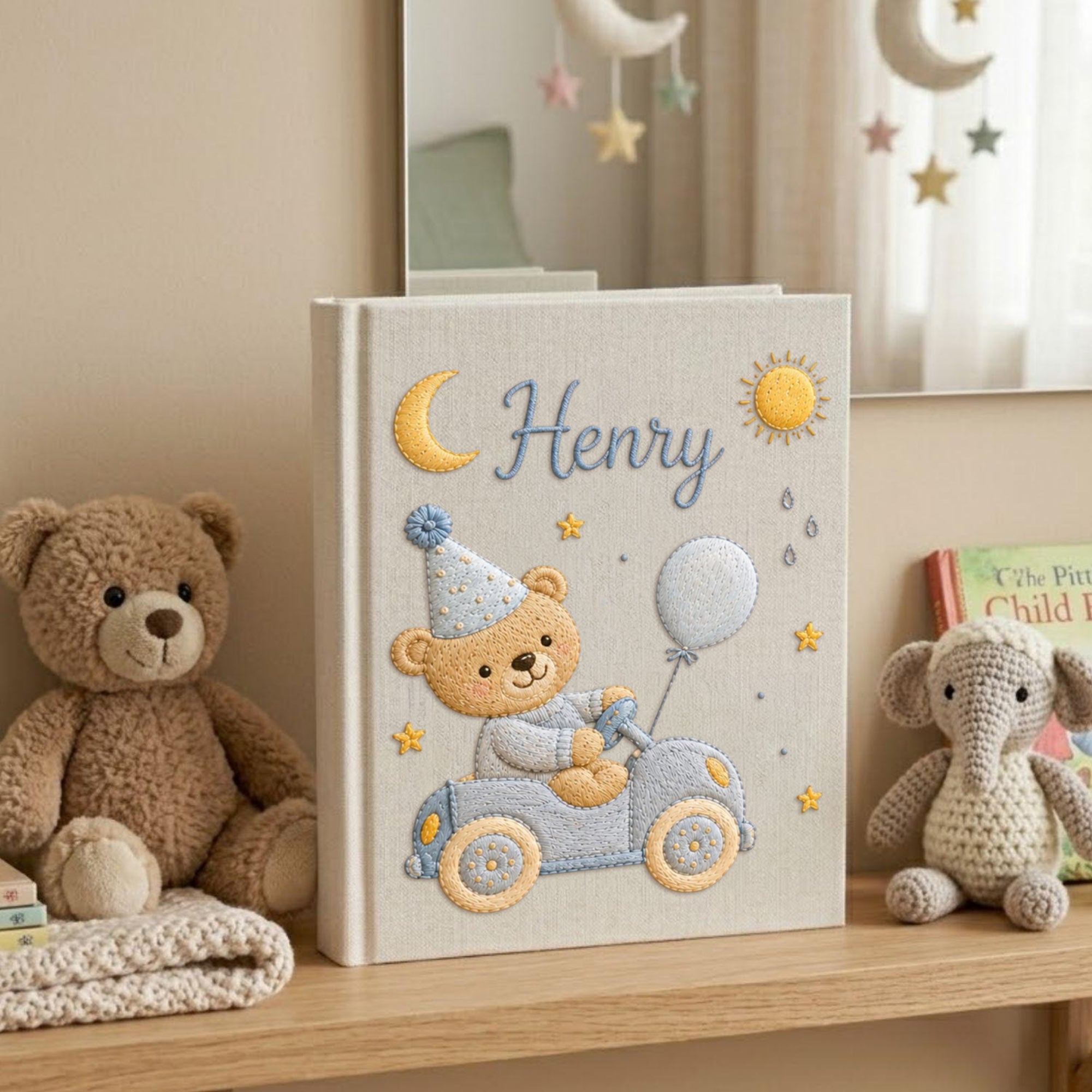 Personalized hand embroidered baby photo album featuring teddy bear driving a pastel blue vintage car with balloon, moon, stars, and sunshine accents