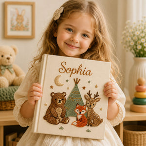 Personalized hand embroidered photo album featuring woodland animals including a bear fox and deer gathered around a teepee on a linen cover