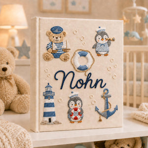 Personalized hand embroidered nautical baby photo album with sailor teddy bear, penguins, lighthouse, and anchor design