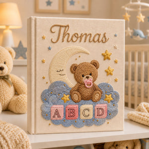 Personalized hand embroidered photo album featuring a teddy bear with a pacifier sitting on clouds beneath a crescent moon with colorful ABC blocks and stars