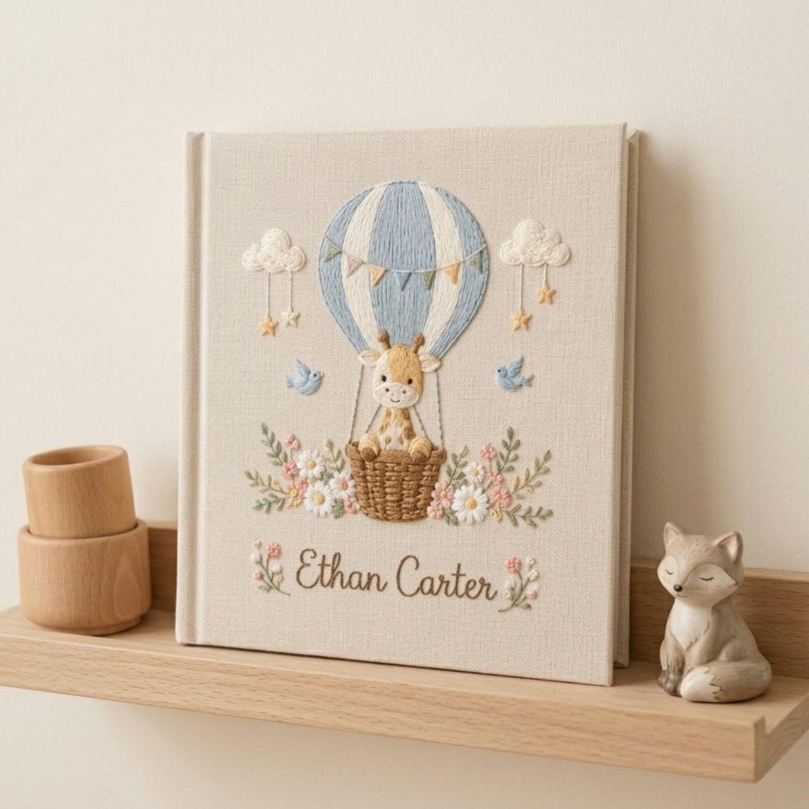 Personalized hand embroidered photo album featuring a baby giraffe in a hot air balloon with flowers clouds birds and custom name embroidery