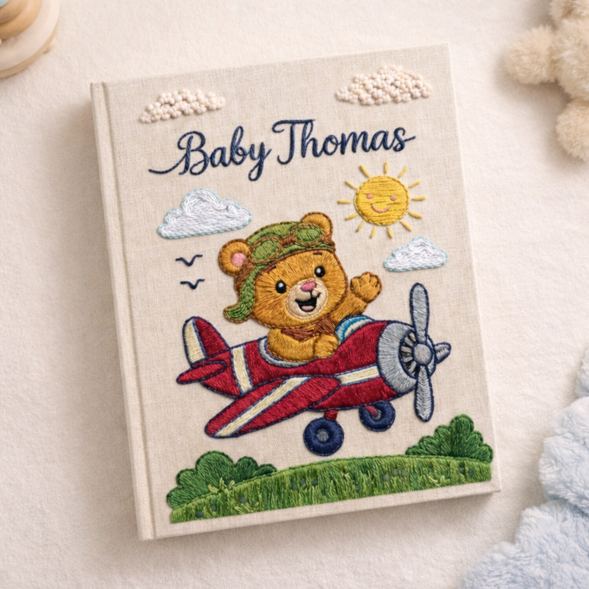 Personalized hand embroidered photo album featuring a teddy bear pilot flying a vintage red airplane beneath clouds and sunshine on a premium linen cover