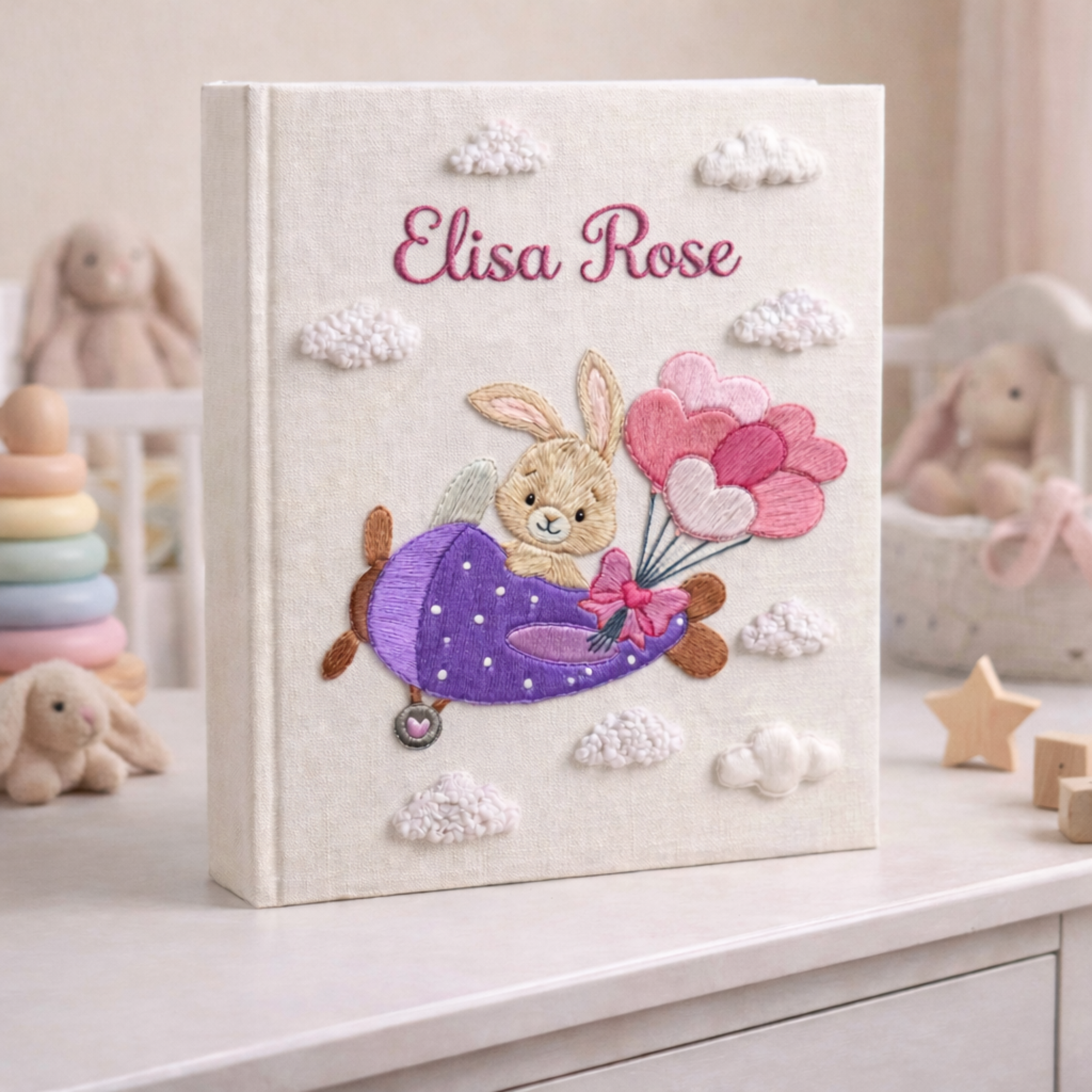 Personalized hand embroidered photo album featuring a bunny flying a purple airplane with heart-shaped balloons and fluffy clouds