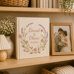 Custom lavender floral embroidered wedding photo albums with pastel botanical wreaths, daisy flowers, and personalized couple names on linen covers