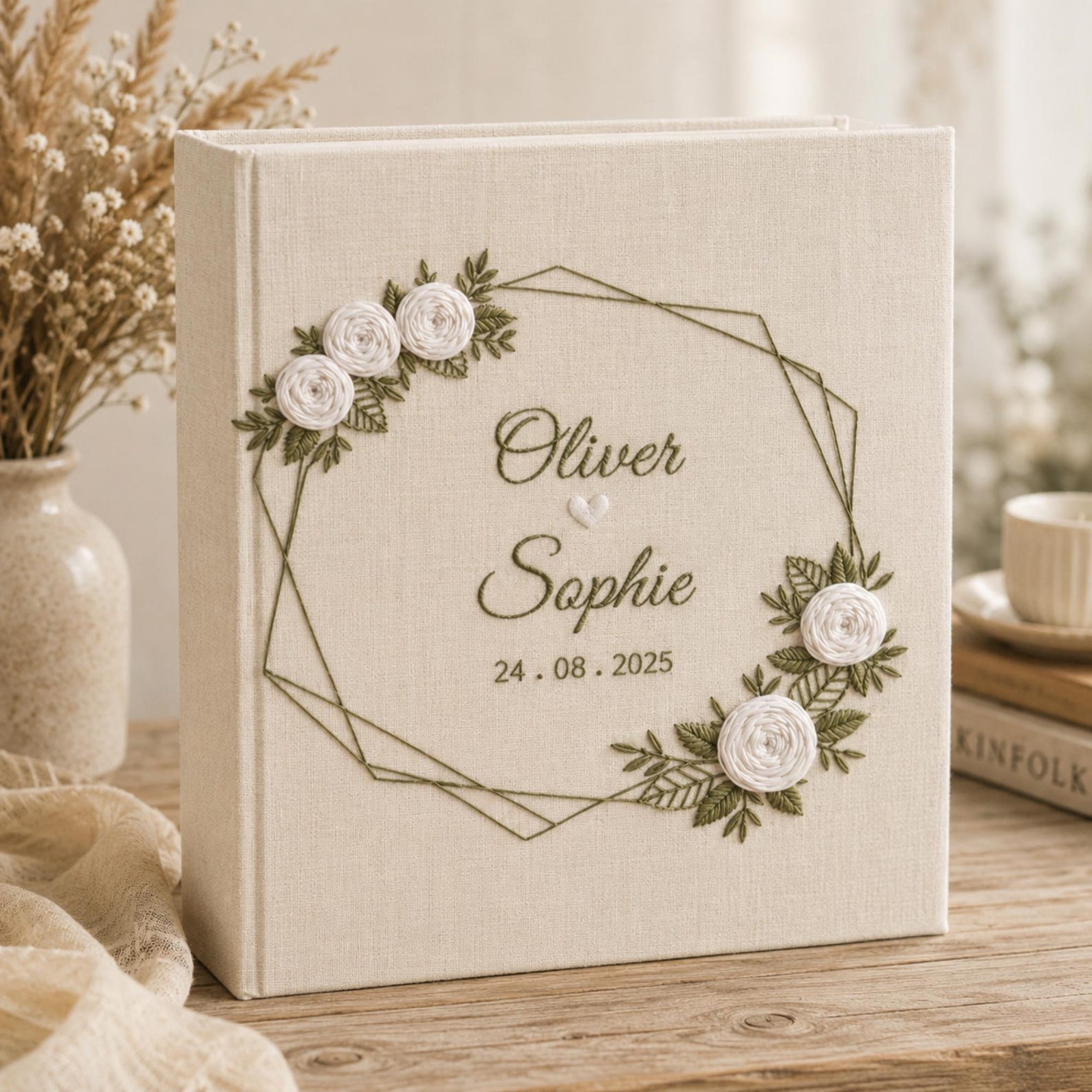 Neutral floral embroidered wedding albums with ivory roses, botanical wreaths, geometric floral frames, and personalized couple names on linen covers