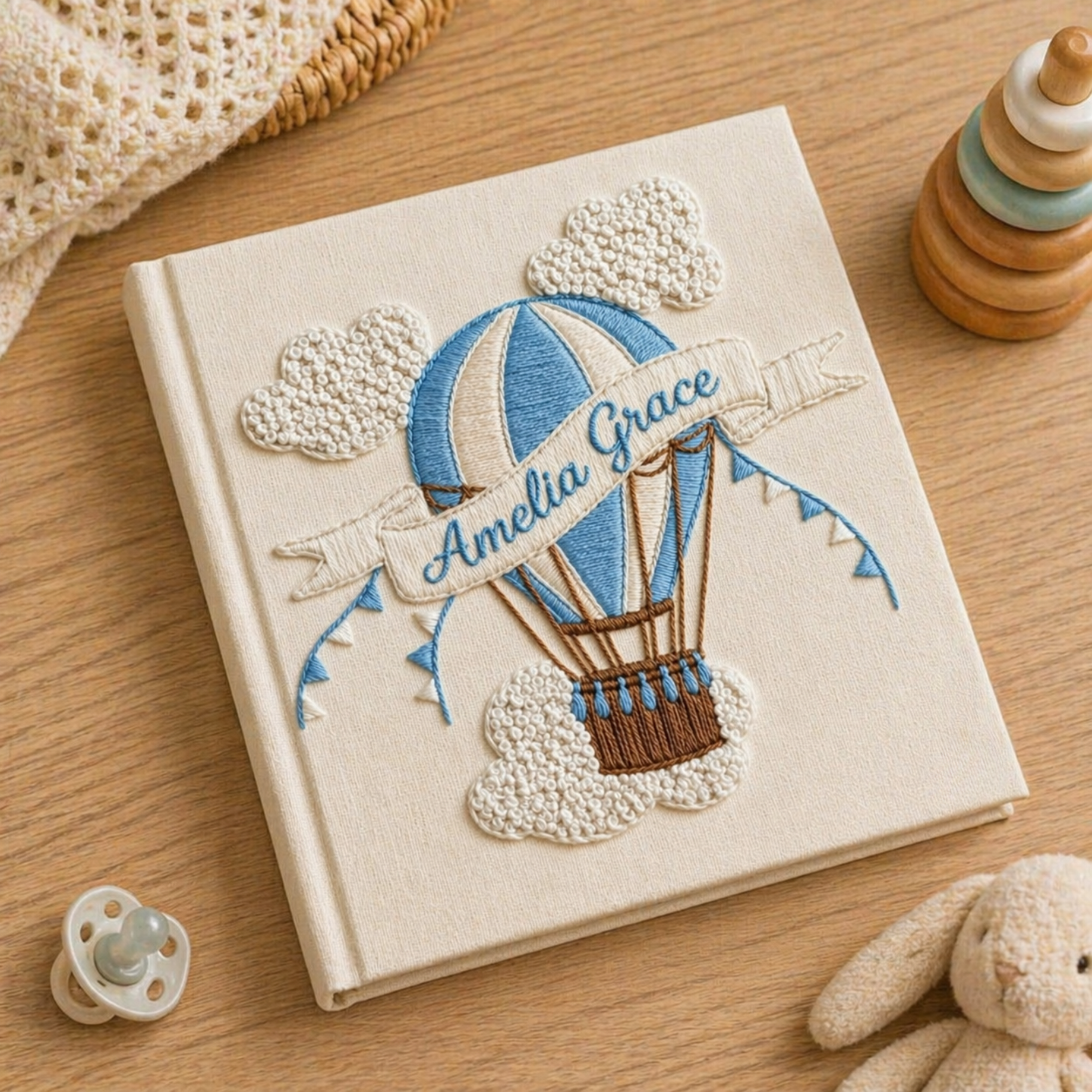 Personalized hand embroidered photo album featuring a vintage hot air balloon floating among clouds and stars on a linen cover