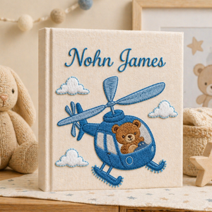 Personalized hand embroidered photo album featuring an aviator teddy bear flying a vintage airplane through fluffy clouds with custom name embroidery