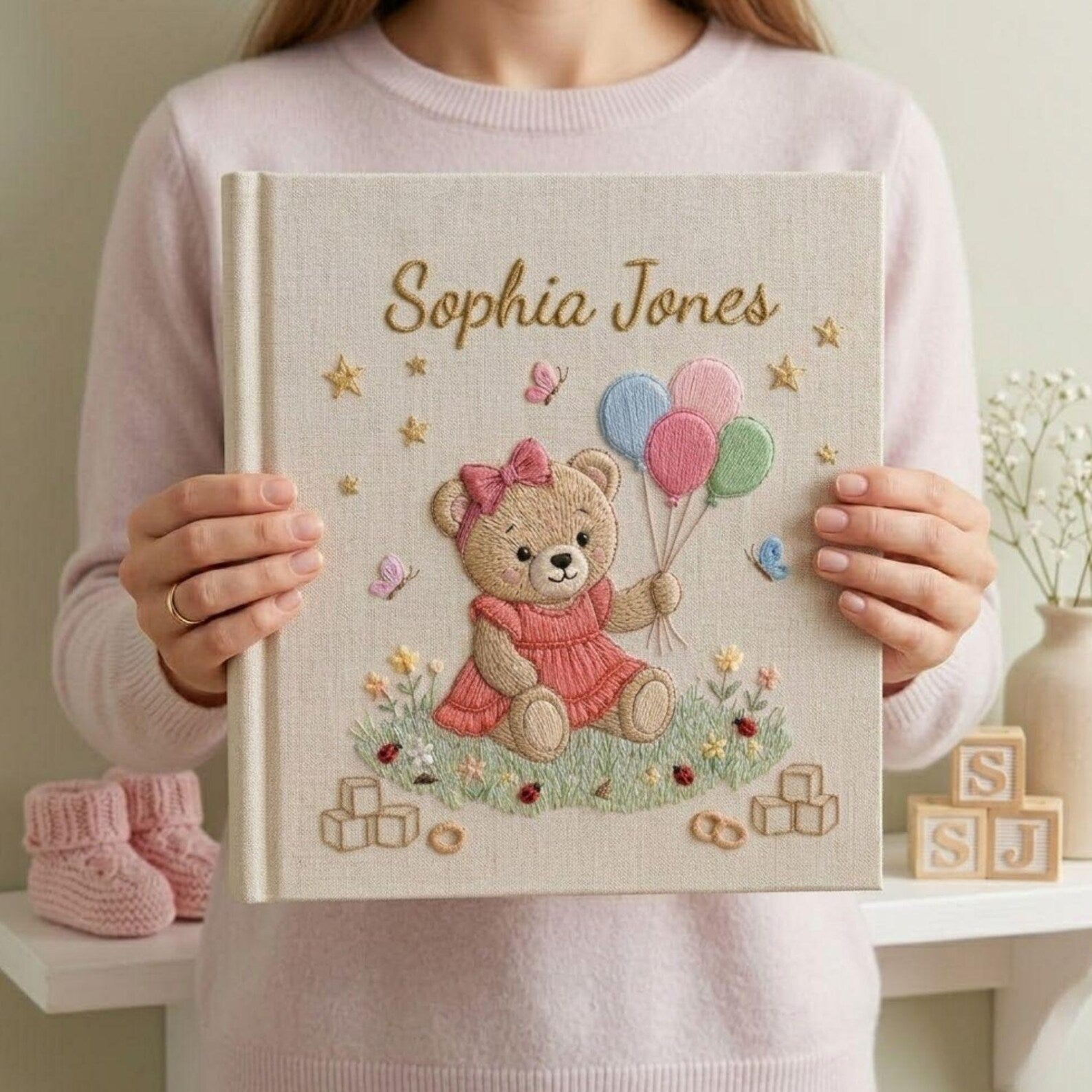 Personalized hand embroidered photo album featuring teddy bear holding pastel balloons surrounded by flowers butterflies and custom baby name