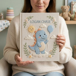 Personalized hand embroidered photo album featuring a cute blue dinosaur holding a balloon with sunshine and cloud details on a linen cover