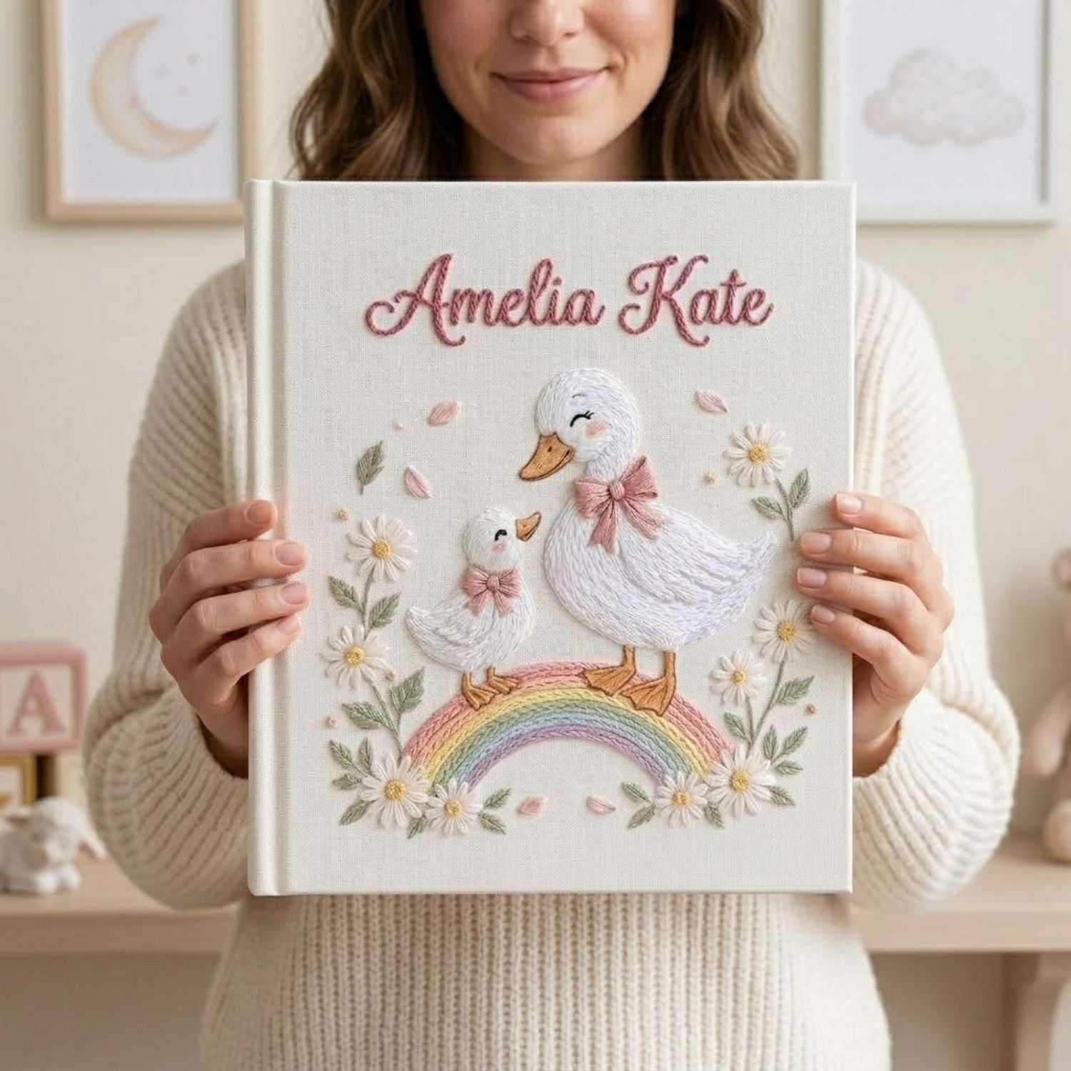 Personalized hand embroidered photo album featuring a swan mother and baby standing on a pastel rainbow surrounded by daisies and floral details