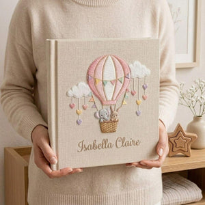 Personalized hand embroidered photo album featuring an elephant and bunny in a pastel hot air balloon with hanging hearts and custom name embroidery