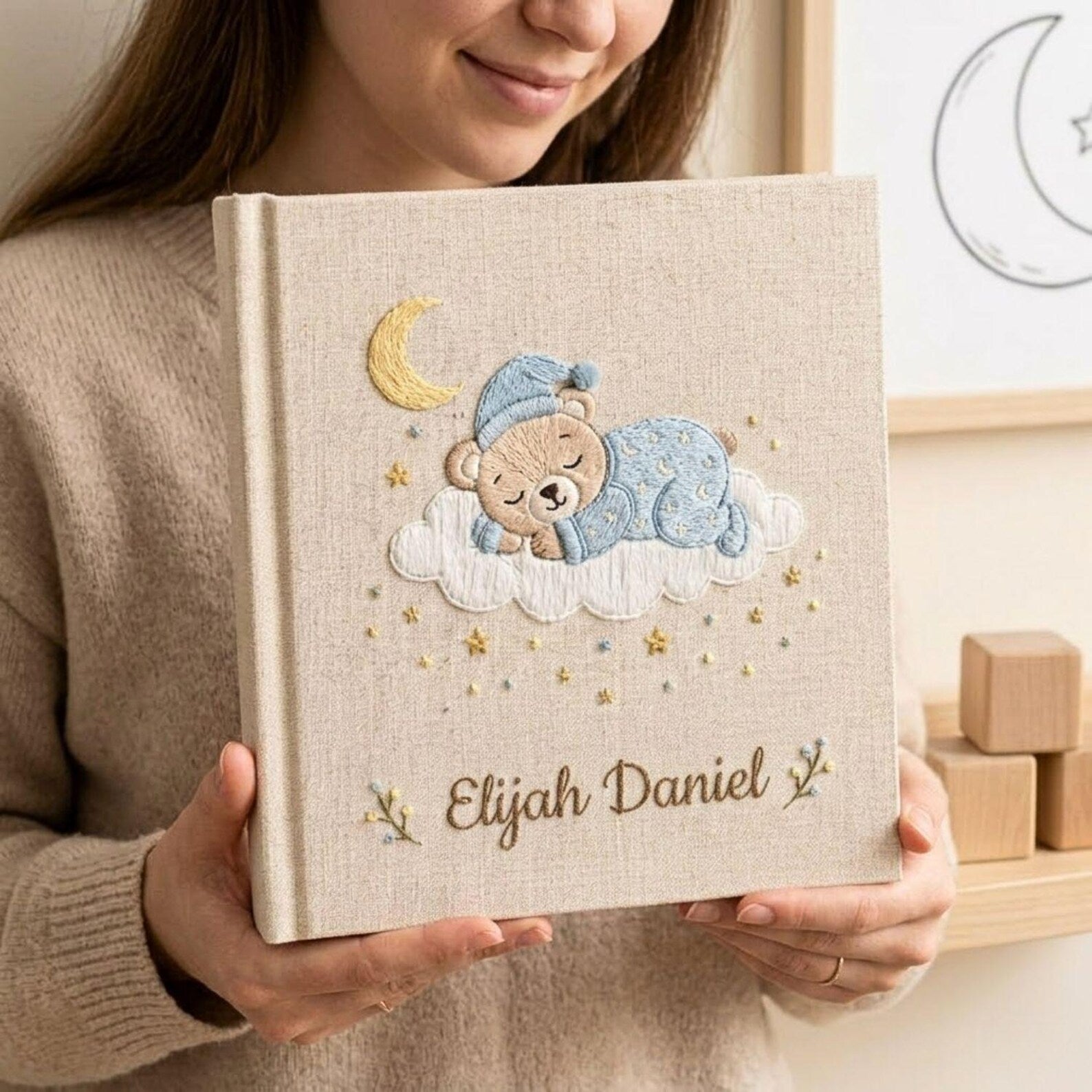 Personalized hand embroidered photo album featuring a sleeping teddy bear on a cloud beneath a crescent moon with custom name embroidery