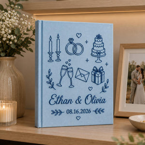 Personalized embroidered wedding photo album with wedding icons rings champagne cake and custom couple names on linen cover