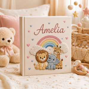 Personalized hand embroidered photo album featuring lion elephant and giraffe under a pastel rainbow with custom name embroidery