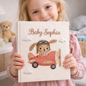 Personalized hand embroidered photo album featuring a bunny flying a purple airplane with heart-shaped balloons and fluffy clouds