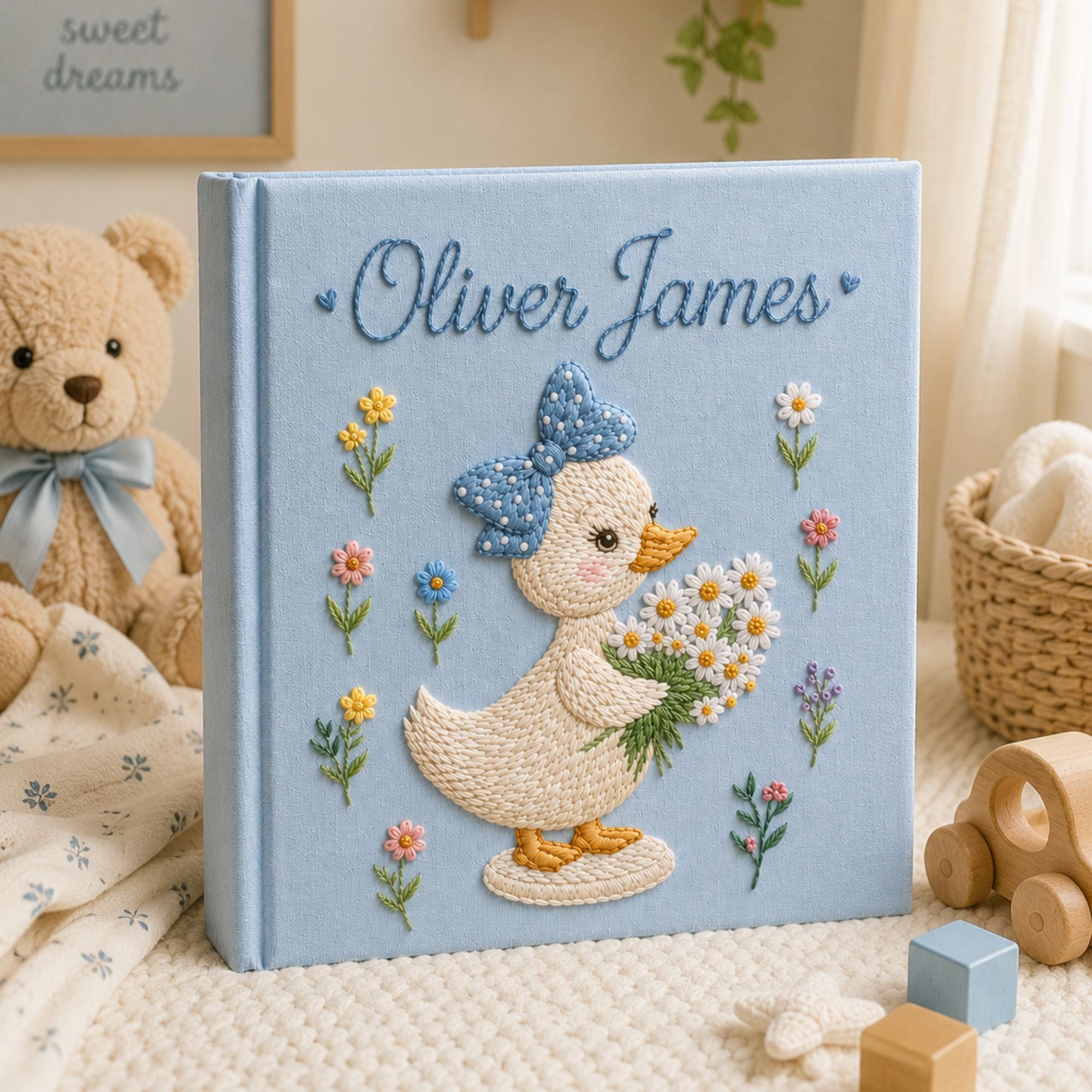 Personalized hand embroidered photo album featuring a cute duckling with a polka dot bow holding a daisy bouquet surrounded by pastel flowers and custom name embroidery