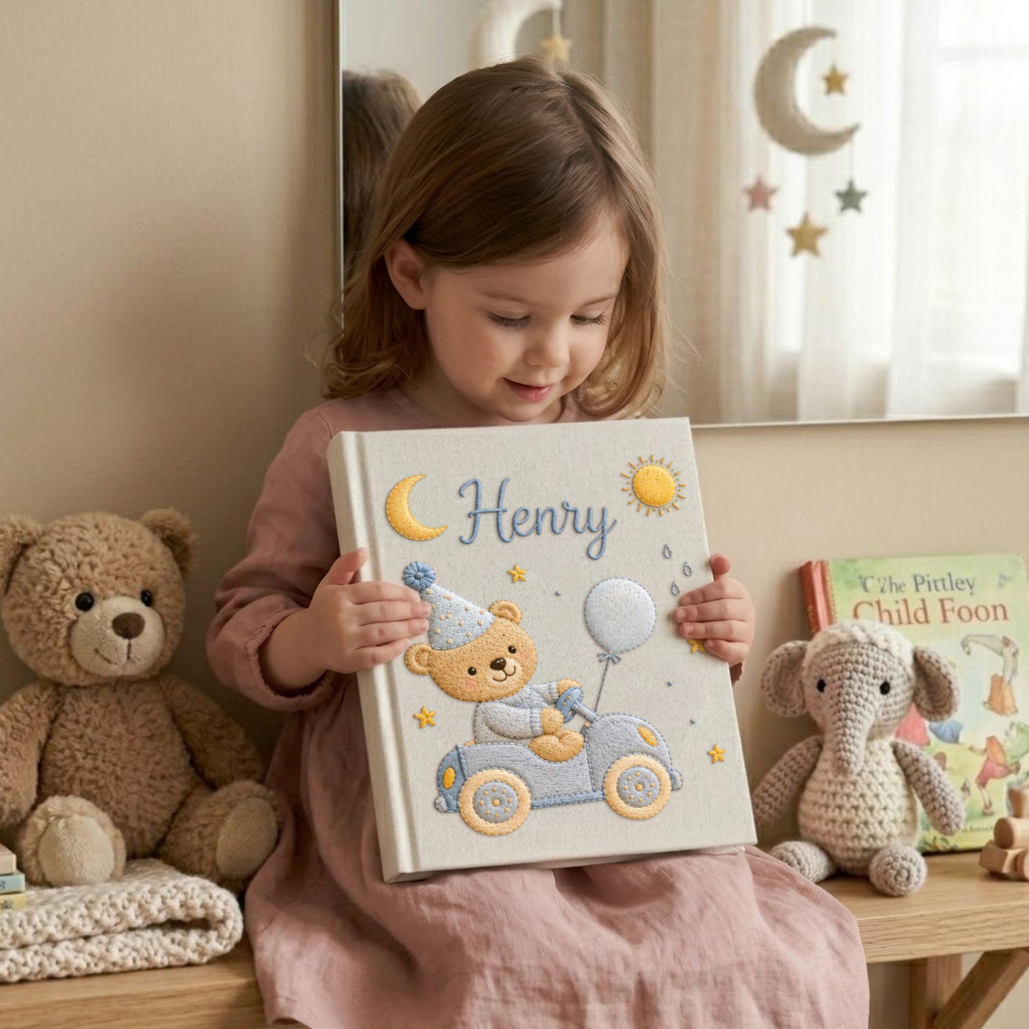 Personalized hand embroidered baby photo album featuring teddy bear driving a pastel blue vintage car with balloon, moon, stars, and sunshine accents
