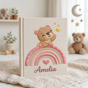 Personalized hand embroidered baby photo album featuring teddy bear sitting on pastel rainbow with stars and heart accents