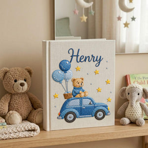 Personalized hand embroidered baby photo album featuring teddy bear riding a blue vintage car with balloons and stars on linen cover